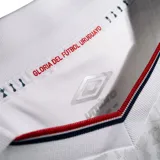 Camiseta de fútbol Umbro del Club Nacional de Football, modelo Home 2026. Diseño en color blanco con tejido jacquard que presenta un patrón de trofeos históricos en toda la prenda. Incluye cuello con detalles tricolores, logo de Umbro, escudo del club con estrellas y sponsors estampados en el frente y mangas.