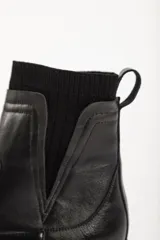 Bota tipo chelsea de caña media en color beige, con suela track dentada y paneles laterales elásticos acanalados.