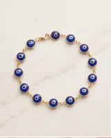 Pulsera de plata 925 con baño de oro y dijes circulares de ojo turco en color azul.