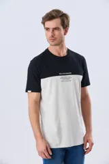 Remera de algodón y poliéster de corte clásico, con diseño en bloques de color negro en la parte superior y gris melange en la inferior. Presenta cuello redondo, mangas cortas y un pequeño estampado tipográfico en el pecho.