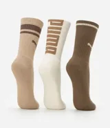 Kit de tres pares de medias deportivas Puma de caña larga. Un par es beige con dos rayas marrones y logo de Puma. Otro par es blanco liso. El tercer par es marrón oscuro con dos rayas blancas y logo de Puma. Todas están confeccionadas en algodón.