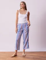 Pantalón capri de algodón estampado a rayas verticales en tonos celeste, rosa y beige. Tiene pretina elastizada, bolsillos delanteros y tajos laterales con botones.