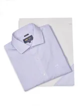 Camisa de vestir de manga larga, corte regular fit, color celeste pálido con finas rayas verticales en tono oscuro. Presenta cuello clásico y bolsillo en el pecho con un pequeño logo bordado de un ave.