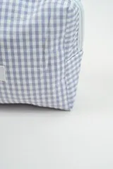 Neceser de tela con estampado de cuadros vichy en color verde y blanco. Cuenta con una etiqueta frontal con el logo de la marca y un tirador de cierre en color rosado.