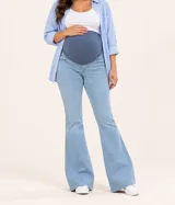 Jean maternal de corte bootcut confeccionado en denim celeste claro, con faja alta de tejido elástico azul oscuro para soporte abdominal.