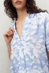 Camisa estampada de manga corta con cuello solapa y botones de nácar al frente, confeccionada en un tejido liviano de sutil textura que aporta movimiento y frescura.
