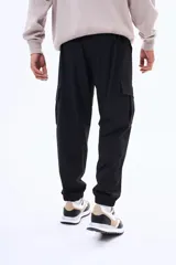 Pantalon cargo negro de corte holgado, con bolsillos laterales con solapa y puños elásticos en los tobillos. Cuenta con cintura elástica con cordón de ajuste.