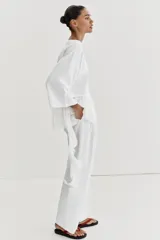 Camiseta de algodón con cuello redondo y manga corta. Presenta un bajo asimétrico confeccionado en un tejido ligero con volantes y una tira lateral decorativa con volantes.