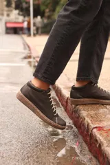 Zapatillas acordonadas de cuero color negro con suela marrón. Diseño artesanal de producción local.