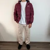 Campera tipo puffer color bordó con capucha, cierre frontal blanco y puños de tejido elástico. Presenta el logo de la marca bordado en el pecho.