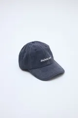 Gorra azul oscuro con efecto lavado, costuras pespunteadas en color blanco y texto bordado en el frente.