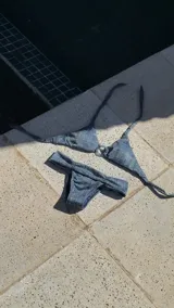 Conjunto de bikini con estampado a cuadros, compuesto por un corpiño triangular con argolla y tiras para atar al cuello y espalda, y una bombacha vedetina ancha con frunces delanteros y traseros.