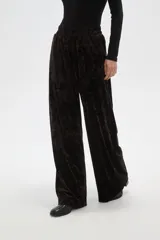 Pantalon de corte ancho y tiro alto, confeccionado en tela de terciopelo con acabado brillante. Presenta cintura elástica y pinzas frontales que aportan volumen y caída fluida a la prenda.