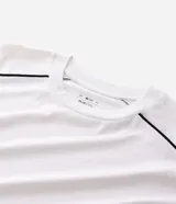 Remera de algodón color blanco, con cuello redondo, manga corta y detalle de raya negra contrastante que recorre la parte superior de los hombros y mangas. Diseño de corte holgado.