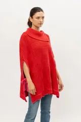 Capa tipo poncho tejido de punto en algodón color rojo con cuello alto y aberturas laterales con lazos rosados.