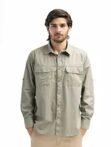 Camisa color verde oliva confeccionada en algodón, de manga larga con cuello clásico y dos bolsillos frontales con tapa y velcro. Presenta abertura en la espalda con red interna para mayor respiración y manga remangable con botón para fijar.