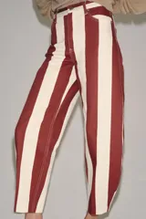 Jeans de tiro alto con corte barrel y diseño de rayas verticales en color bordó y beige. Presenta cierre frontal con cremallera y botón, trabillas en la cintura y bolsillos funcionales en delantero y espalda.