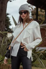 Camisa blanca con volados frontales y mangas largas.