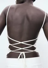 Top halter blanco de crochet con diseño entallado, espalda abierta con tirantes finos cruzados y detalles de ondas en los bordes.