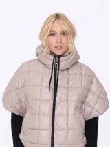 Campera corta color beige con capucha, cierre frontal con cremallera y mangas cortas. Diseño acolchado con patrón de rombos.