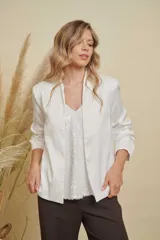 Chaqueta de satén color blanco, con diseño abierto sin botones, cuello mao y mangas largas con puños rectos.
