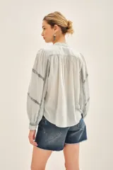 Camisa celeste de voile con cuello redondo, cartera con botones, corte recto y volados frontales.