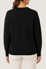Buzo de punto color negro, con cuello redondo, mangas largas con puños ajustados y diseño con tajos laterales en el ruedo.