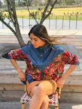Camisa oversize combinada que mezcla denim azul en la parte superior y mangas, con tela vintage de estampado geométrico y tribal multicolor en la espalda y mangas. Presenta cuello camisero y corte holgado.