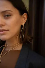 Aros colgantes dorados con forma de líneas onduladas.