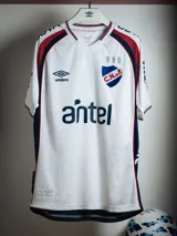Camiseta de fútbol Umbro de golero del Club Nacional de Football, modelo oficial 2026. Diseño en color blanco con detalles en rojo y azul en los hombros, cuello y laterales, con escudo del club y sponsor Antel en el frente.