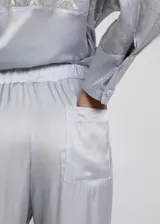 Pantalón cropped de tiro alto con cintura elástica ajustable mediante lazo. El tejido es ligero y presenta un acabado ligeramente satinado, en un tono celeste o gris muy claro.