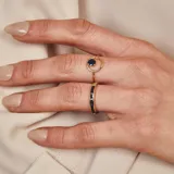 Anillo de oro 18k con diseño minimalista que presenta un zafiro azul engastado en un círculo abierto.