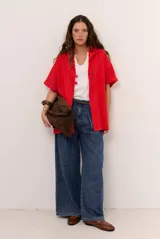 Sobrecamisa roja de lino de manga corta, con cuello solapa, costuras decorativas en contraste y cierre frontal con presillas y botones alargados.