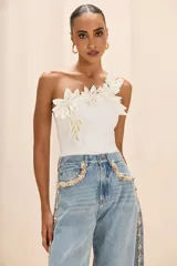 Top blanco de un solo hombro, con aplicaciones florales en relieve y hojas en el escote.