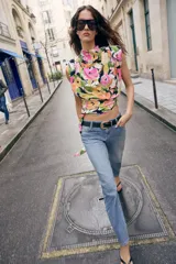 Jeans de tiro medio con corte slim fit, confeccionados en denim azul clásico. Presentan diseño de cinco bolsillos, cierre frontal con cremallera y botón, e incluyen un cinturón negro con hebilla metálica.