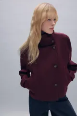 Abrigo corto de paño con mezcla de lana, color bordó. Presenta cuello subido, cierre frontal cruzado con botones, mangas largas con trabillas decorativas y bolsillos laterales de vivo.