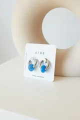 Aros de argolla en acero quirúrgico con dije de piedra natural en tono azul.