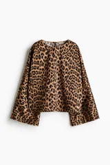 Blusa de corte holgado con estampado animal print de leopardo, escote redondo y mangas largas amplias.