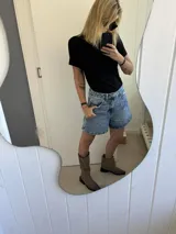 Botas de caña media confeccionadas en cuero gamuzado color marrón oscuro. Presentan un diseño versátil 2 en 1 que permite usar la caña extendida o doblada, con puntera cuadrada y taco bajo.