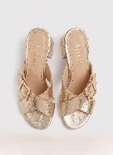 Sandalia de taco ancho color dorado, confeccionada en cuero vacuno, con diseño de tiras cruzadas y hebilla metálica decorativa.