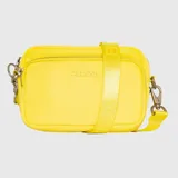 Cartera tipo bandolera de tamaño compacto, confeccionada en material sintético de color fucsia vibrante. Presenta cierre metálico en el compartimento principal, bolsillo frontal con cierre y correa ajustable con logo grabado. Incluye herrajes metálicos y tarjetero interior.