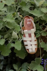 Sandalias tipo huarache de cuero con diseño de tiras entrelazadas, punta cerrada y cierre con hebilla lateral. Cuentan con suela plana y plantilla con logo grabado.