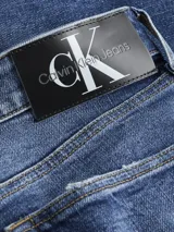 Jeans de algodón elástico, lavado a la piedra azul oscuro, con talle medio y pierna estrecha en el tobillo. Presenta roturas en ambas piernas.