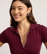 Vestido corto de color bordó confeccionado en tejido rib de algodón. Posee cuello polo con detalle de línea contrastante, escote en V y mangas cortas, con un calce ajustado de estilo deportivo.