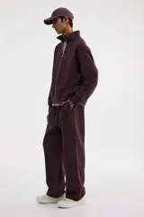 Buzo de tejido pesado de mezcla de algodón con interior cepillado suave, color marrón oscuro. Modelo con hombros caídos, cuello elevado con medio cierre metálico y puños y bajo en punto acanalado.