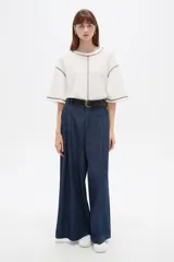 Pantalón de jean azul oscuro, tiro alto, corte ancho y holgado, con bolsillos y frunces en la cintura.