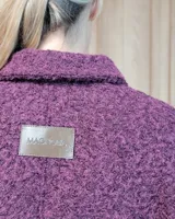 Chaqueta de textura bouclé en color bordó, con corte oversize, cuello camisero, cierre frontal y bolsillos laterales.