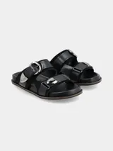 Sandalia de cuero negro con diseño de doble tira ancha, hebillas metálicas grandes y detalles de apliques plateados estilo western.
