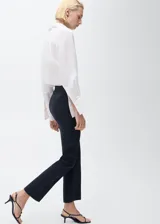 Pantalón de corte recto y diseño crop, color negro, con trabillas en la cintura, dos bolsillos laterales y cierre frontal de gancho y cremallera.