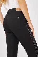 Pantalón de jean negro de corte slim, con tiro alto y detalles de strass plateados en los laterales.